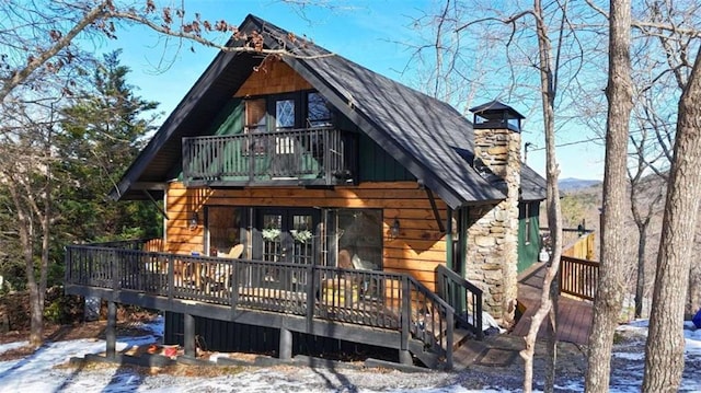 snow covered property featuring a balcony and a deck