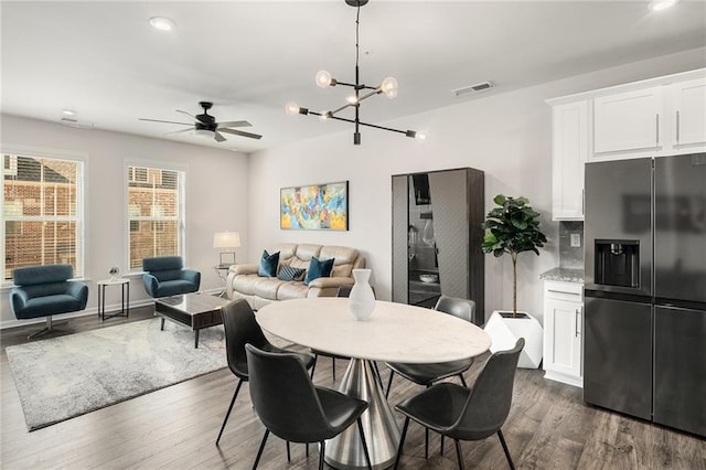 dining space featuring dark wood-type flooring and ceiling fan with notable chandelier