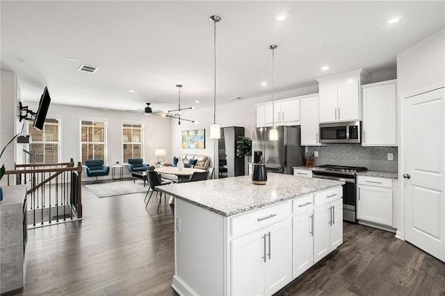 kitchen featuring white cabinetry, dark hardwood / wood-style floors, stainless steel appliances, pendant lighting, and a center island