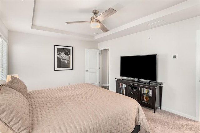 bedroom with ceiling fan, light carpet, and a raised ceiling