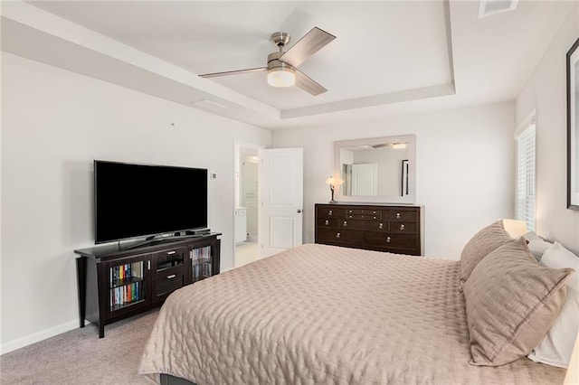 carpeted bedroom featuring a tray ceiling and ceiling fan