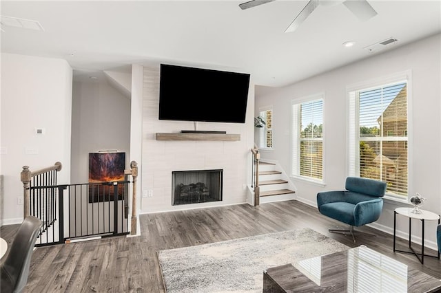 living room featuring a tiled fireplace, hardwood / wood-style flooring, and ceiling fan