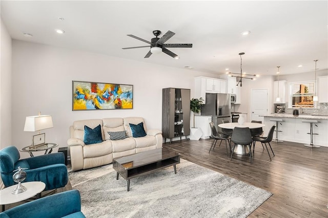 living room with hardwood / wood-style flooring and ceiling fan with notable chandelier