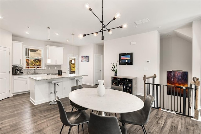 dining space with sink, a chandelier, and dark hardwood / wood-style floors