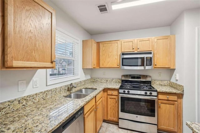 kitchen with light stone countertops, stainless steel appliances, and sink