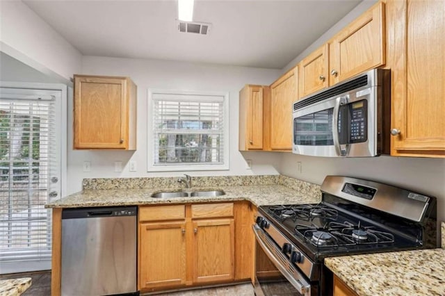 kitchen with light stone counters, light brown cabinets, sink, and stainless steel appliances