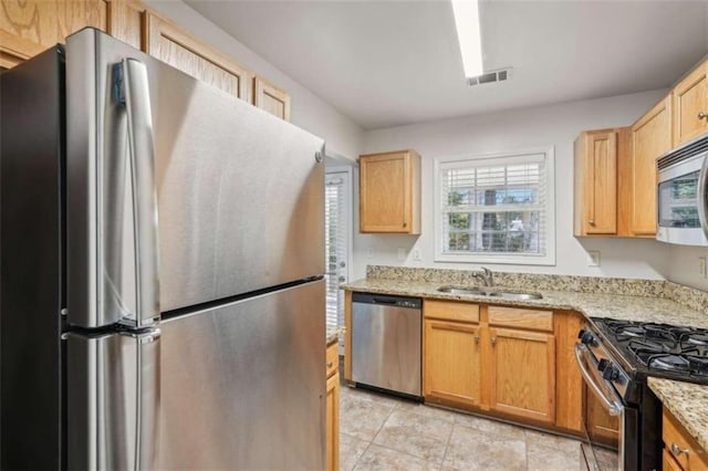 kitchen with light stone counters, sink, and stainless steel appliances