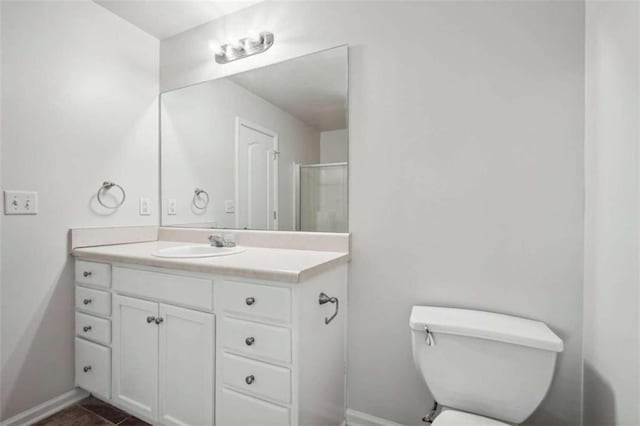 bathroom featuring tile patterned flooring, a shower with door, vanity, and toilet