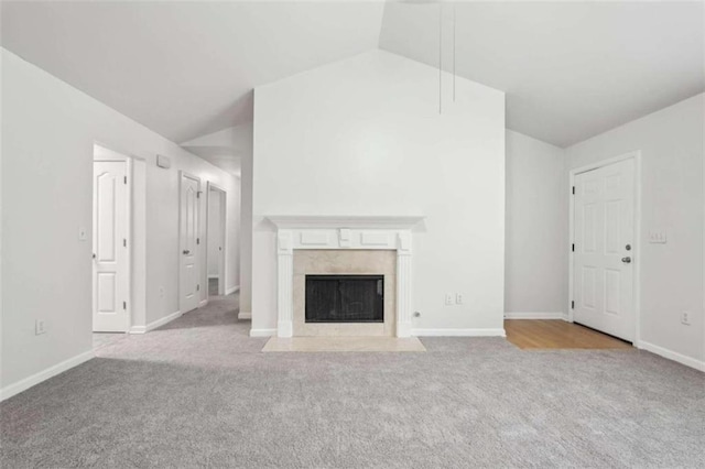 unfurnished living room featuring a premium fireplace, light colored carpet, and vaulted ceiling