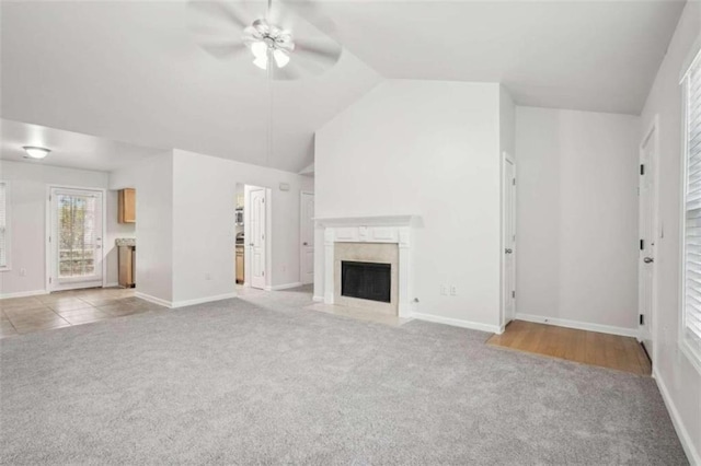 unfurnished living room with ceiling fan, light colored carpet, and vaulted ceiling