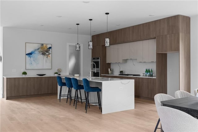 1610 Niskey Lake Rd, Atlanta, GA 30331 - kitchen with modern cabinets, a kitchen breakfast bar, a kitchen island with sink, light wood-type flooring, and stainless steel double oven
