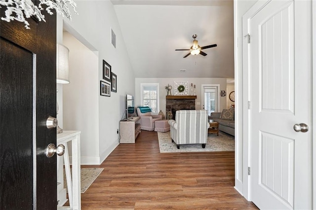 living room featuring lofted ceiling, a fireplace, hardwood / wood-style floors, and ceiling fan