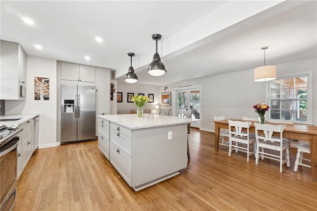 kitchen with light wood-style flooring, a kitchen island, appliances with stainless steel finishes, white cabinetry, and pendant lighting