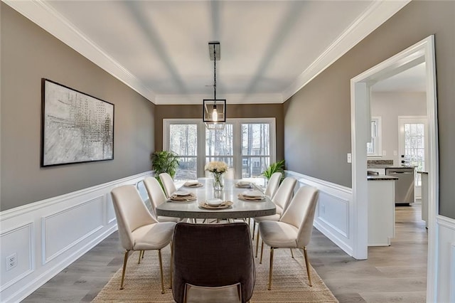 dining room with crown molding and light hardwood / wood-style flooring