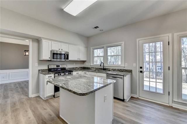 kitchen featuring white cabinetry, stainless steel appliances, sink, and a kitchen island