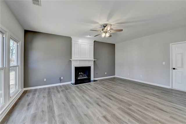 unfurnished living room with ceiling fan, a fireplace, and light wood-type flooring