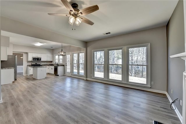 unfurnished living room with sink, light hardwood / wood-style flooring, and ceiling fan