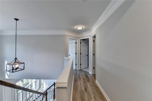 hall featuring an inviting chandelier, crown molding, and light wood-type flooring