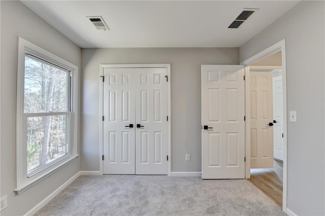 unfurnished bedroom featuring multiple windows, light carpet, and a closet