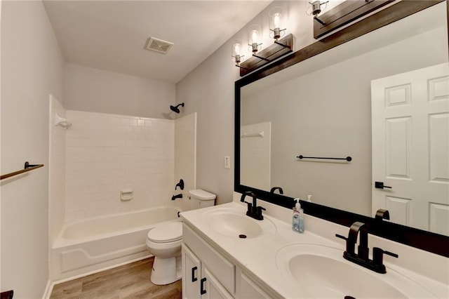 full bathroom with hardwood / wood-style flooring, vanity, toilet, and tiled shower / bath combo