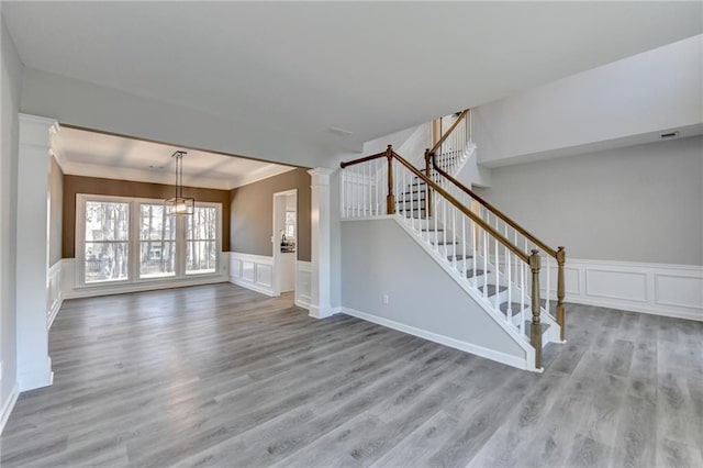 unfurnished living room featuring ornate columns, crown molding, and light hardwood / wood-style flooring