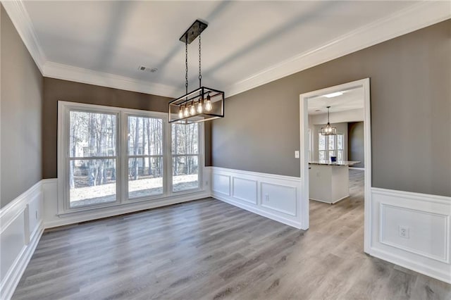 unfurnished dining area featuring ornamental molding and light wood-type flooring