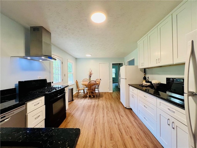 kitchen with black appliances, white cabinetry, a textured ceiling, and range hood