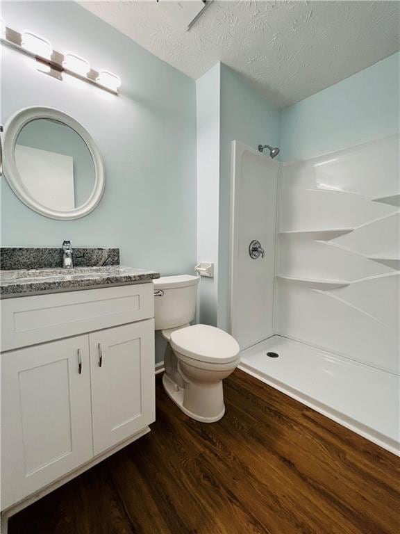 bathroom featuring hardwood / wood-style floors, vanity, a textured ceiling, and walk in shower