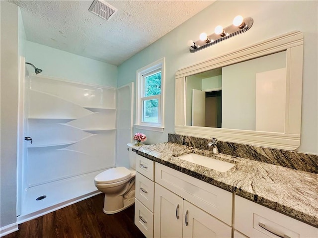 bathroom featuring a textured ceiling, vanity, a shower, hardwood / wood-style floors, and toilet