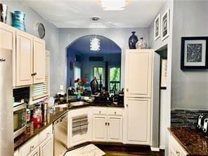 kitchen featuring white cabinetry, dishwasher, sink, dark stone counters, and decorative backsplash