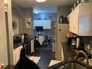 kitchen with backsplash, white cabinetry, and sink