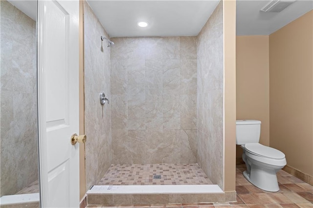 bathroom with tile patterned floors, toilet, and a tile shower