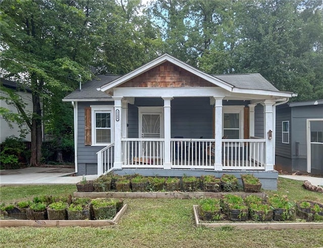 view of front of property with covered porch, a vegetable garden, and a front lawn