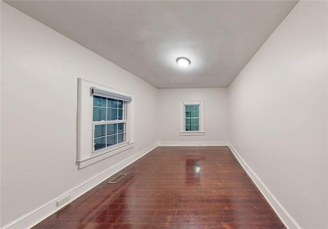 empty room with dark wood-style flooring and baseboards