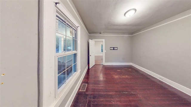 hallway featuring wood finished floors, baseboards, and crown molding
