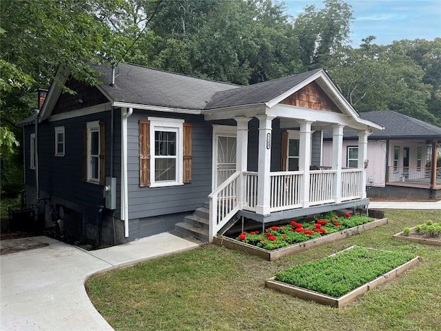 view of front of home with a porch, a front yard, and a shingled roof
