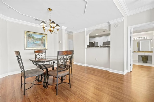 3475 Oak Valley Rd NE Unit 950, Atlanta, GA 30326 - dining area with light wood-style flooring, a chandelier, ornamental molding, baseboards, and arched walkways