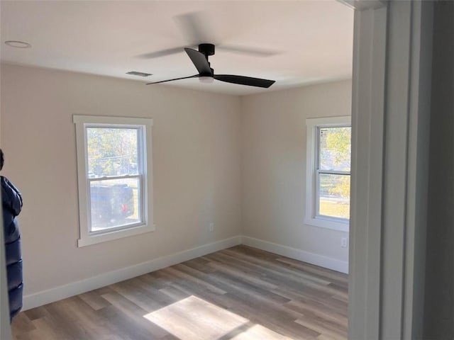 spare room featuring plenty of natural light, baseboards, and wood finished floors