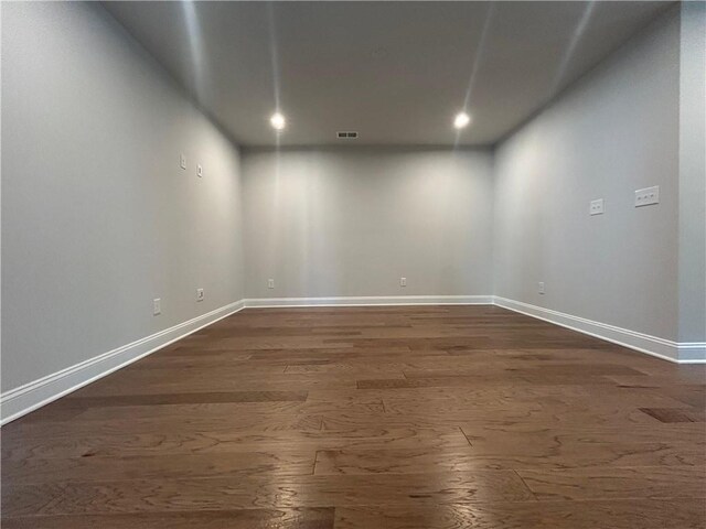 spare room featuring dark wood finished floors, visible vents, and baseboards