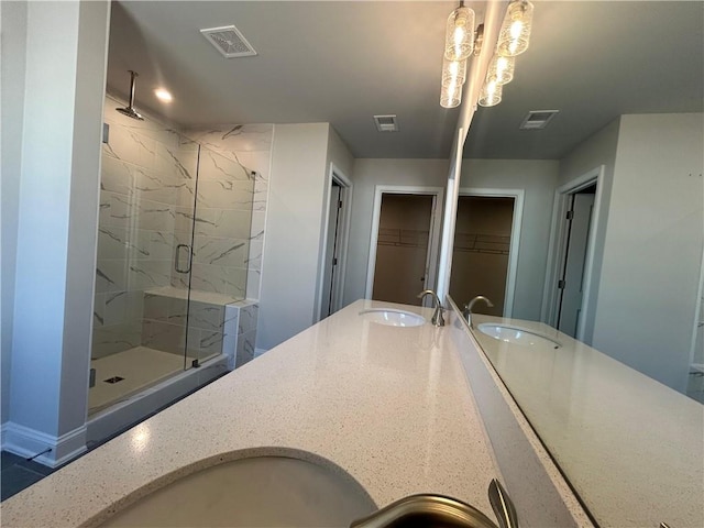 bathroom with visible vents, a sink, a marble finish shower, and a walk in closet