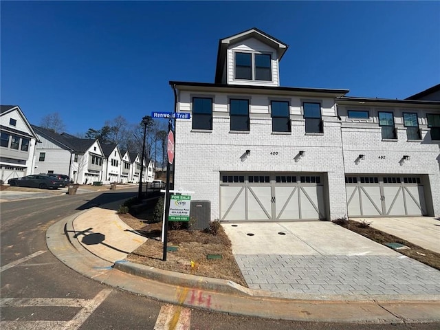 exterior space with driveway, brick siding, an attached garage, and a residential view