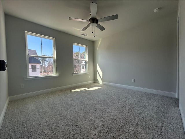 unfurnished room featuring carpet floors, baseboards, visible vents, and ceiling fan