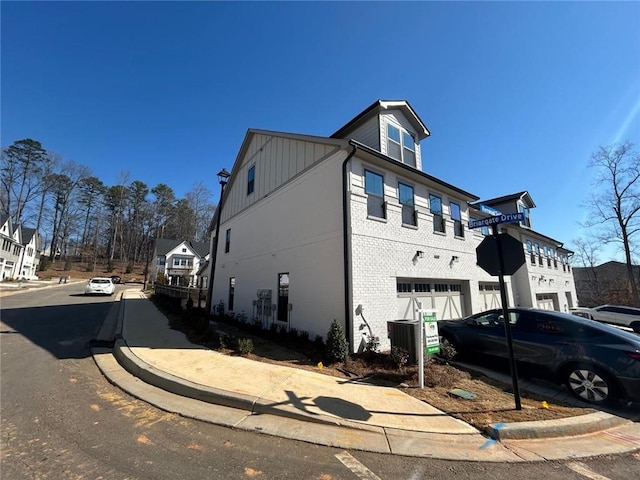 view of property exterior featuring a garage, brick siding, and board and batten siding