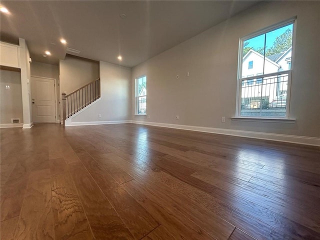 empty room with stairs, recessed lighting, dark wood finished floors, and baseboards