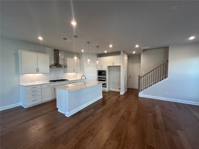 kitchen featuring stainless steel appliances, white cabinets, a sink, and wall chimney range hood