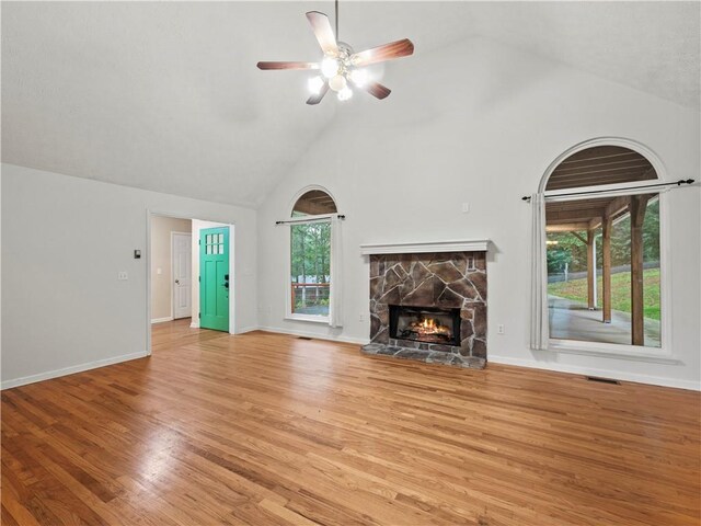 205 Crooked Pine Trl, Baldwin, GA 30511 - unfurnished living room featuring high vaulted ceiling, a stone fireplace, ceiling fan, light wood-style flooring, and baseboards