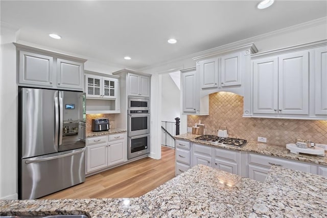 602 Davenport Pl, Canton, GA 30115 - kitchen featuring stainless steel appliances, light wood-type flooring, crown molding, tasteful backsplash, and light stone countertops