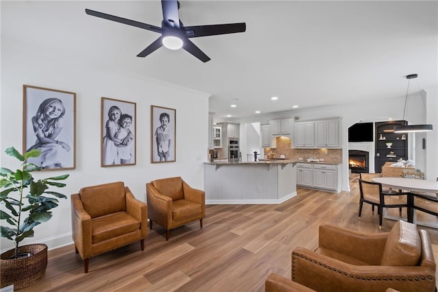 602 Davenport Pl, Canton, GA 30115 - living area featuring a warm lit fireplace, a ceiling fan, crown molding, light wood-type flooring, and recessed lighting