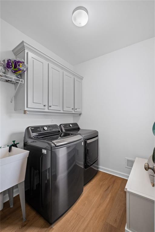 602 Davenport Pl, Canton, GA 30115 - laundry area with washing machine and clothes dryer, cabinet space, light wood-type flooring, and baseboards