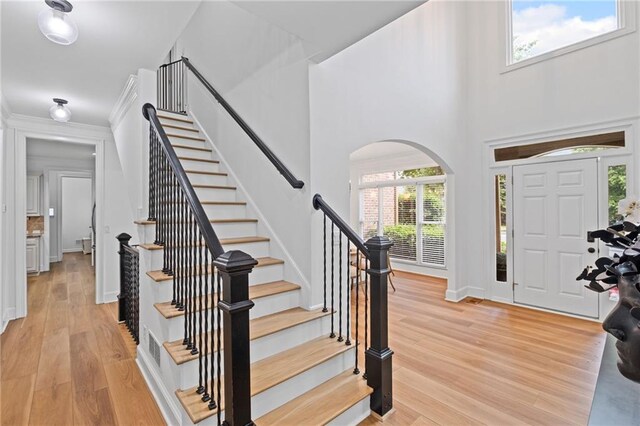 602 Davenport Pl, Canton, GA 30115 - foyer entrance with arched walkways, light wood-style flooring, stairs, a high ceiling, and baseboards